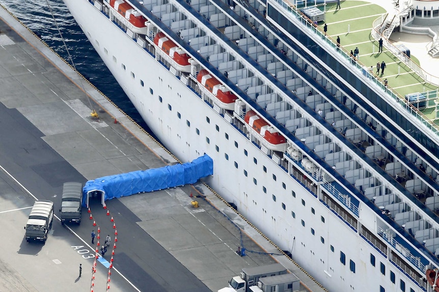 A cruise ship with a walkway from the door covered in blue tarps