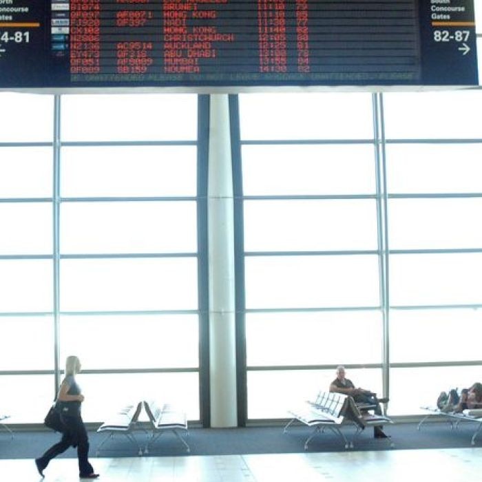 A woman walks beneath a departures board at an international airport