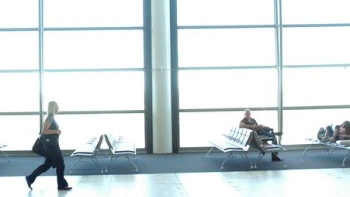 A woman walks beneath a departures board at an international airport