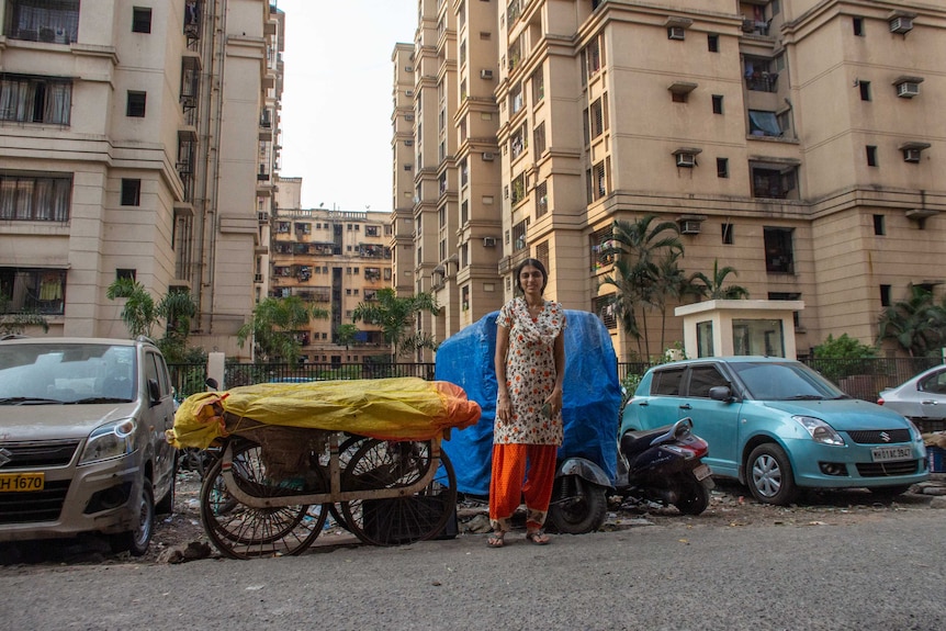 A woman standing in a street with cars and apartments in the background