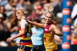 A grinning Brisbane AFLW player runs back down the ground after kicking a goal in finals.