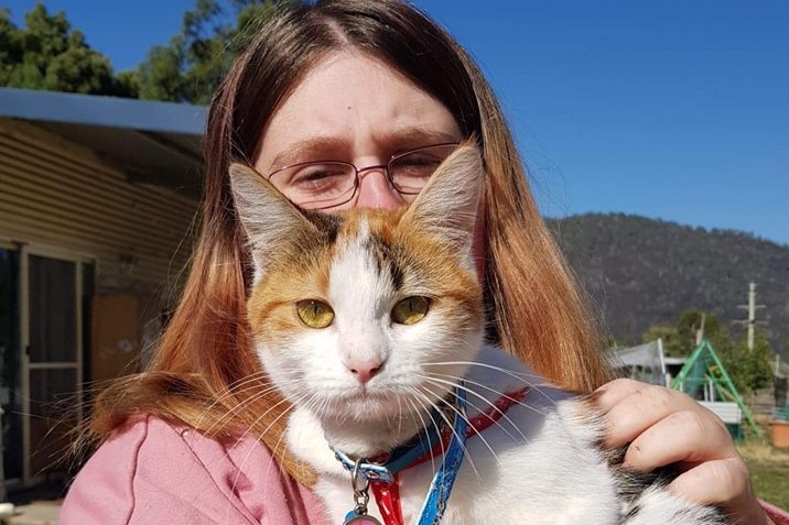 A woman holding a white and ginger cat