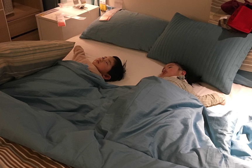 Two kids sleeping in a bed in Beijing's Ikea store
