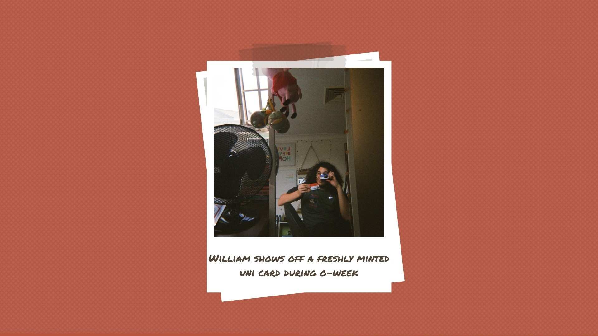 A young man holds a newly minted university ID card in front of a mirror