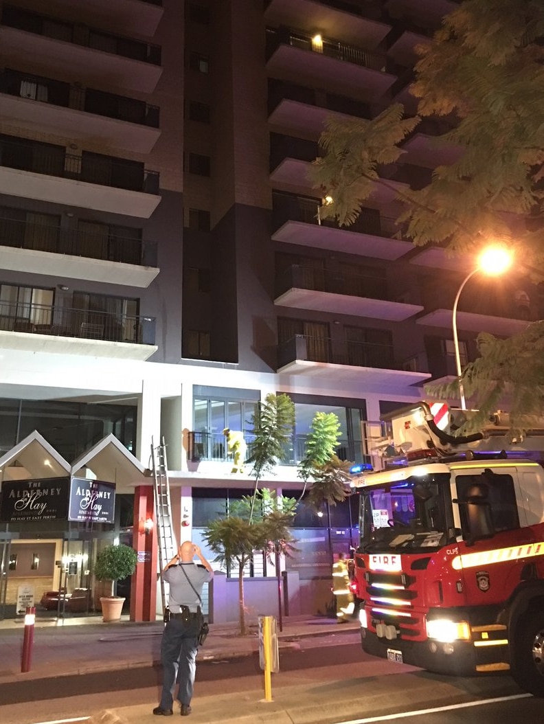 A city apartment complex in the early hours of the morning with a policeman and fire truck outside.