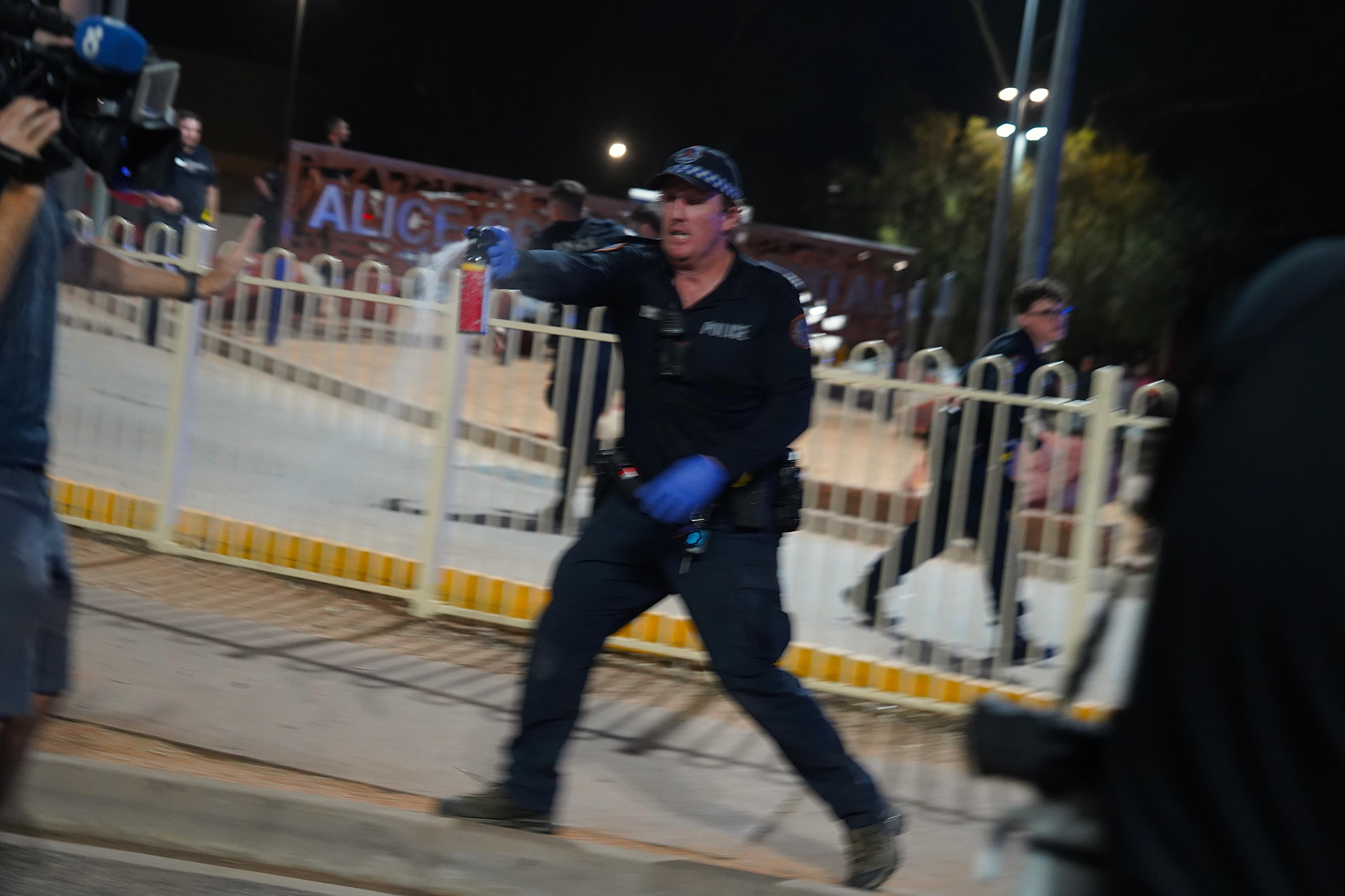 Una foto borrosa de un hombre blanco con uniforme de policía rociando gas pimienta al camarógrafo del Canal 10 que le tendía la mano para detener.