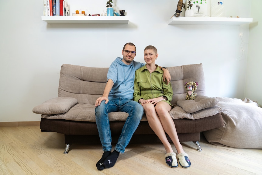 Barbara sits on her couch with the partner in their living room.