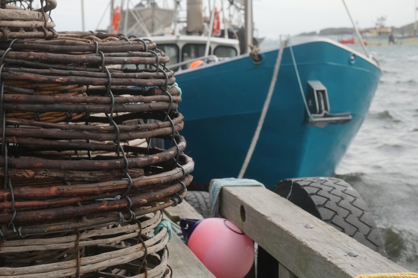 Lobster traps in the foreground with a fishing boat moored nearby.