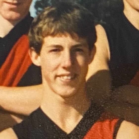 An old photo of Tim, looking to camera, wearing a Leeor red-and-black guernsey 