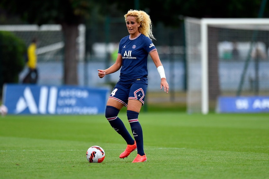 A footballer stands ready to pass the ball in a French women's division one game. 