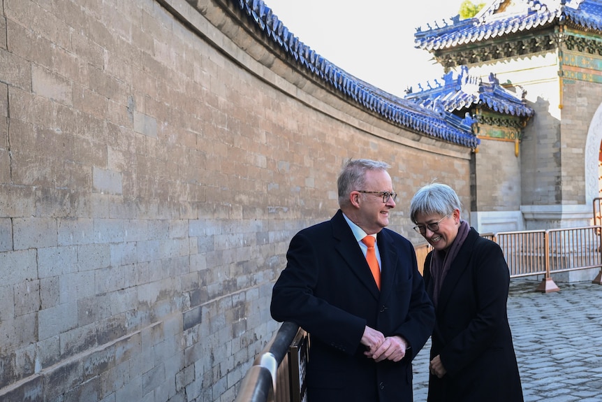 Anthony Albanese and Penny Wong shakes hands beside a wall in China.