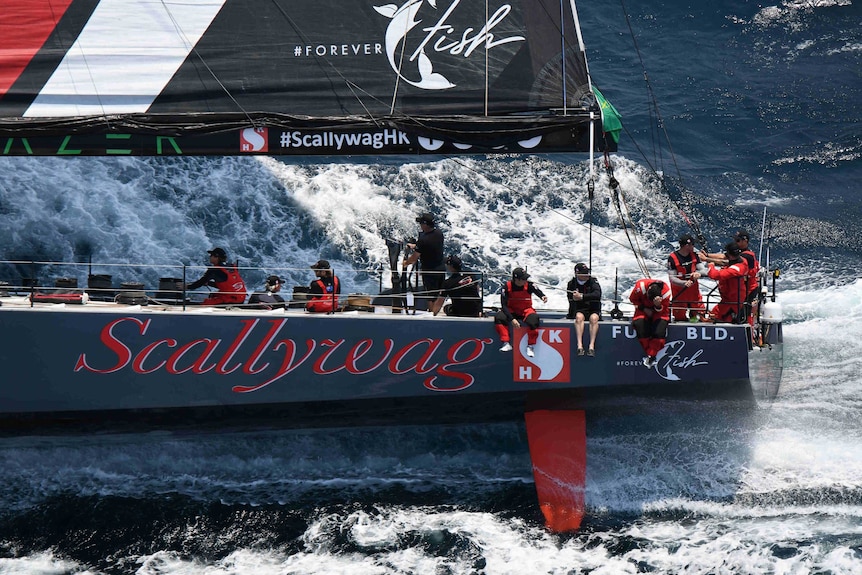 Scallywag, a yacht in the 2019 Sydney Hobart fleet, in the wager. Crew members sit on the side of the yacht