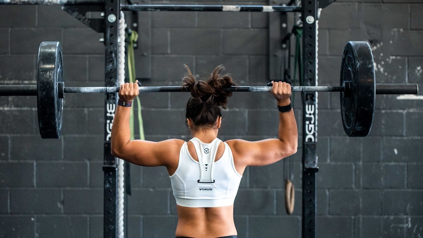 A woman lifts weights in a gym.