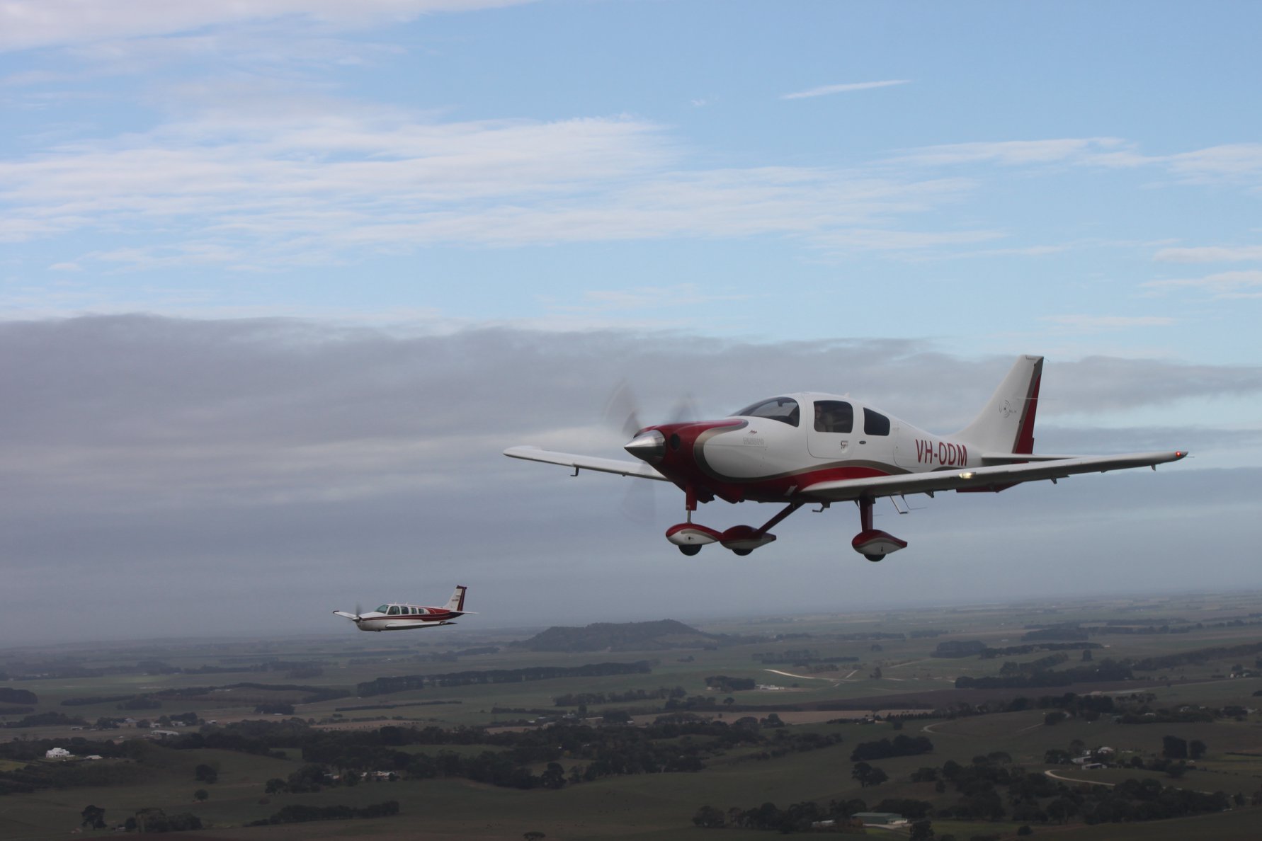 Two light aircraft above a green landscape
