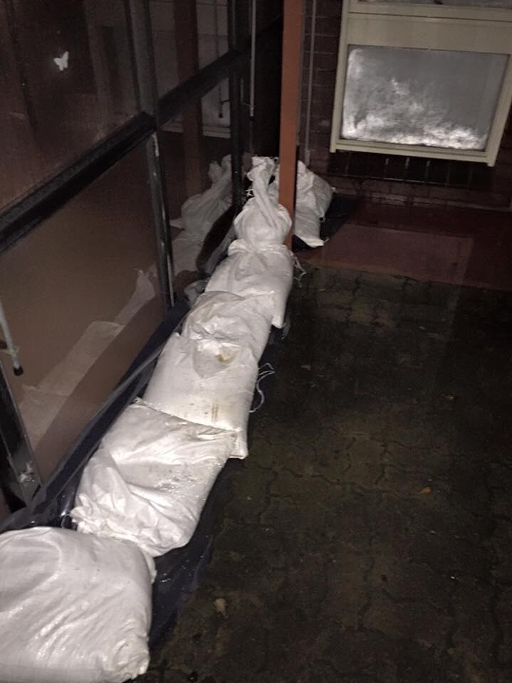 Sandbags inside a house with floodwater rising 100mm outside.