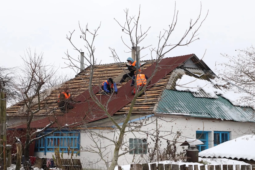 People working on a damaged roof in Ukraine.