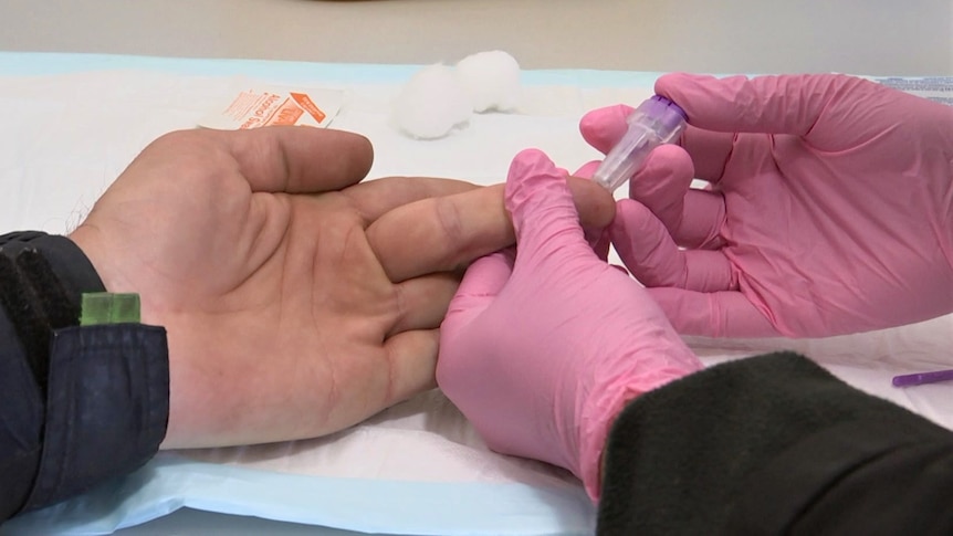 A man getting a test for hepatitis, via a finger-prick test.