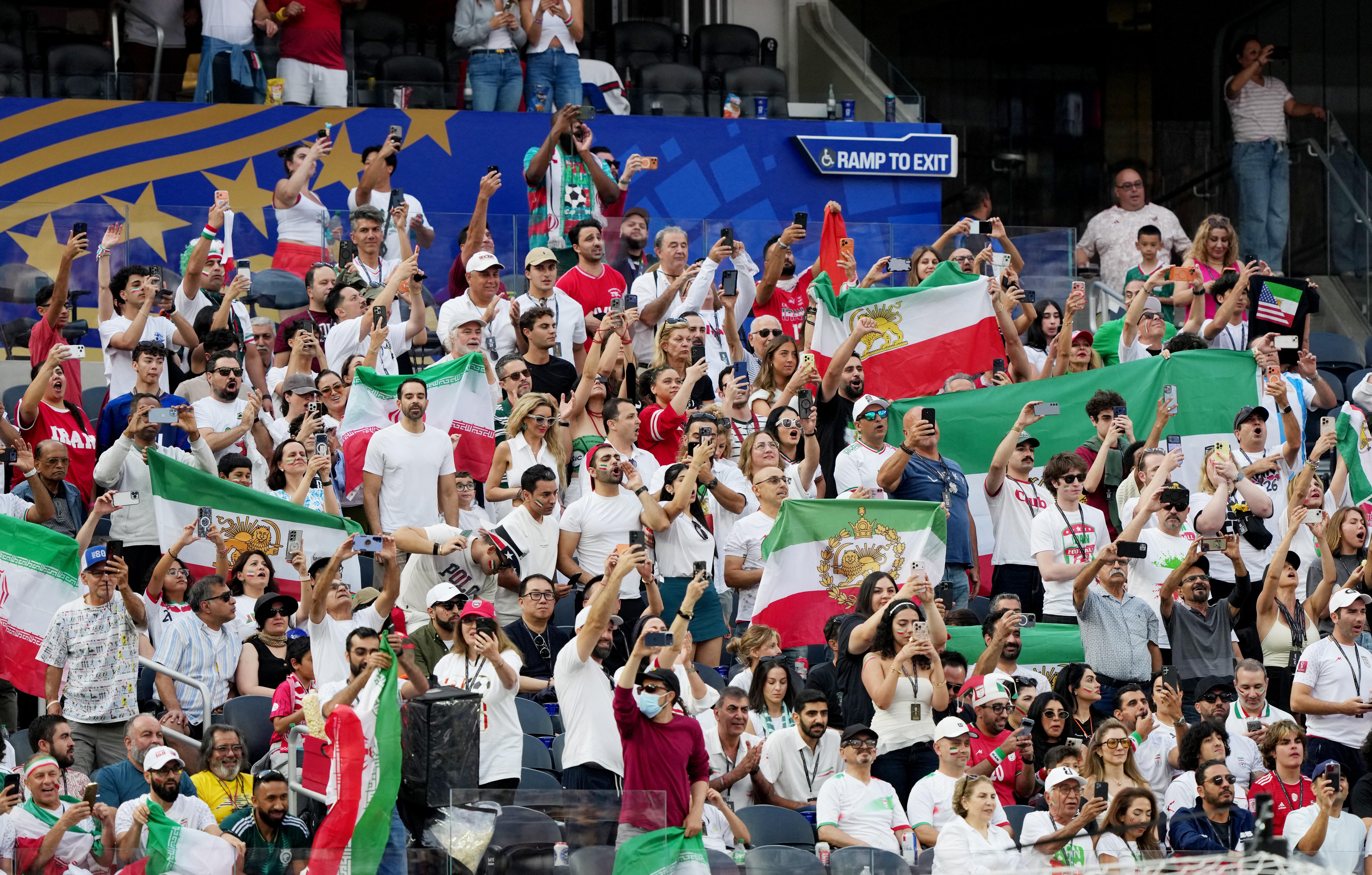 A section of Iran fans inside the stands, waving Lion and Sun flags