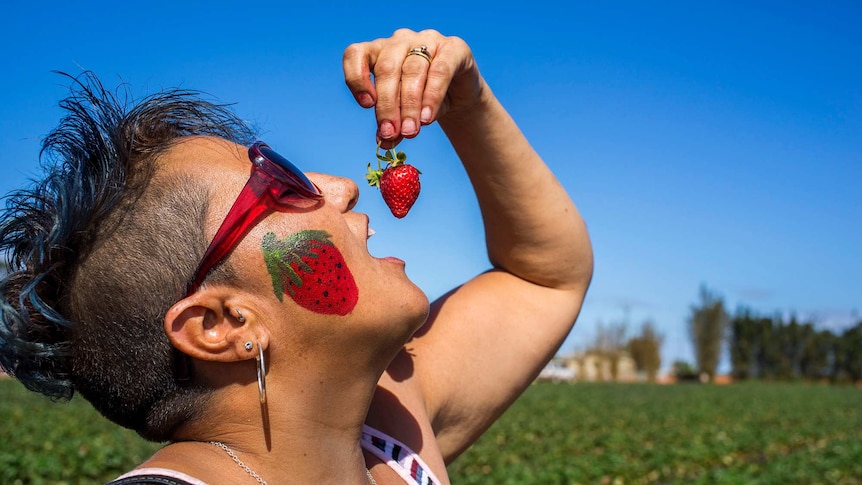 Woman eats strawberry.
