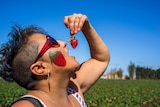 Woman eats strawberry.