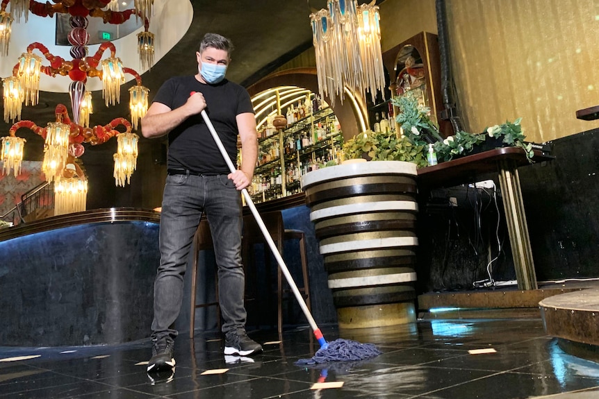 Geoff Slater, owner of Laruche nightclub, wearing a mask while cleaning the floor