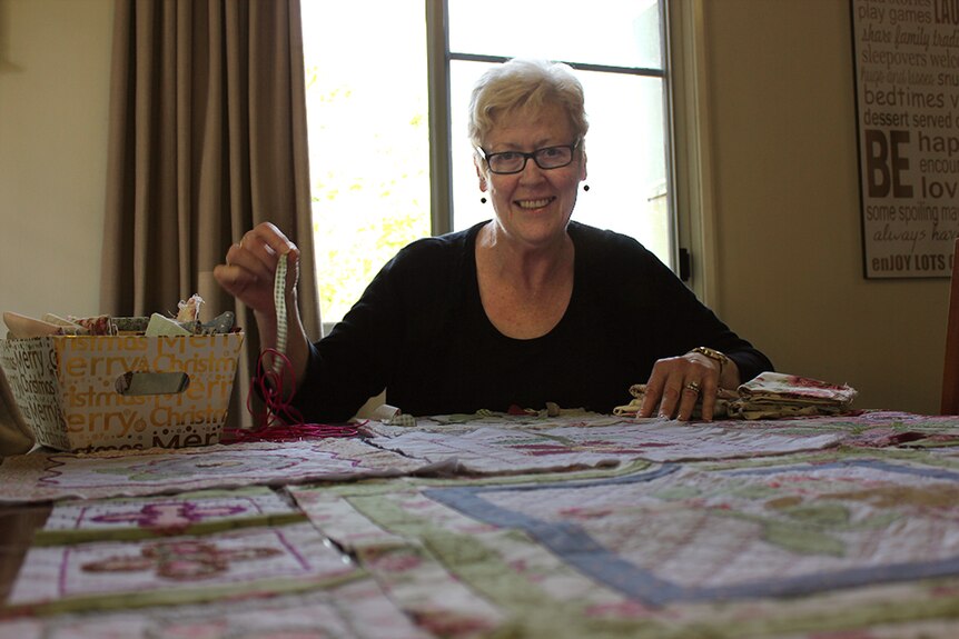 Aileen Gabbert sits in her lounge room looking over the quilt she's currently working on.