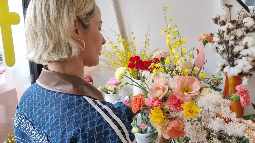 A woman arranges a bunch of flowers.