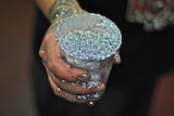 A woman holds a cup full of silver glitter.