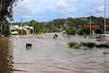 Boys walking through floodwater in Lismore, near a totally inundated service station.