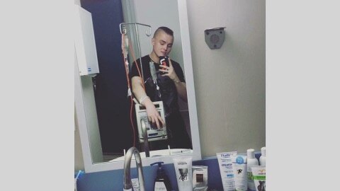 Young man taking a photo in a mirror holding a drip stand