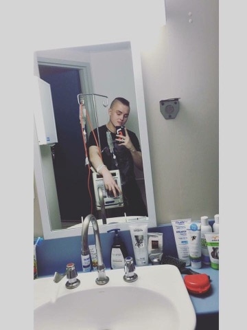 Young man taking a photo in a mirror holding a drip stand