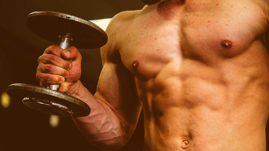 The torso and arm of a muscular man holding a barbell