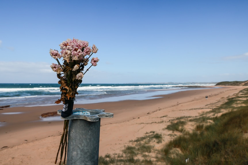 Flowers at a memorial on a beach.