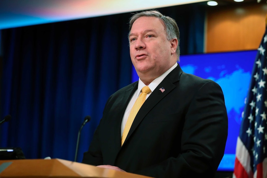 Mike Pompeo speaks behind a lecturn in a yellow tie