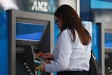 A woman uses an ATM.