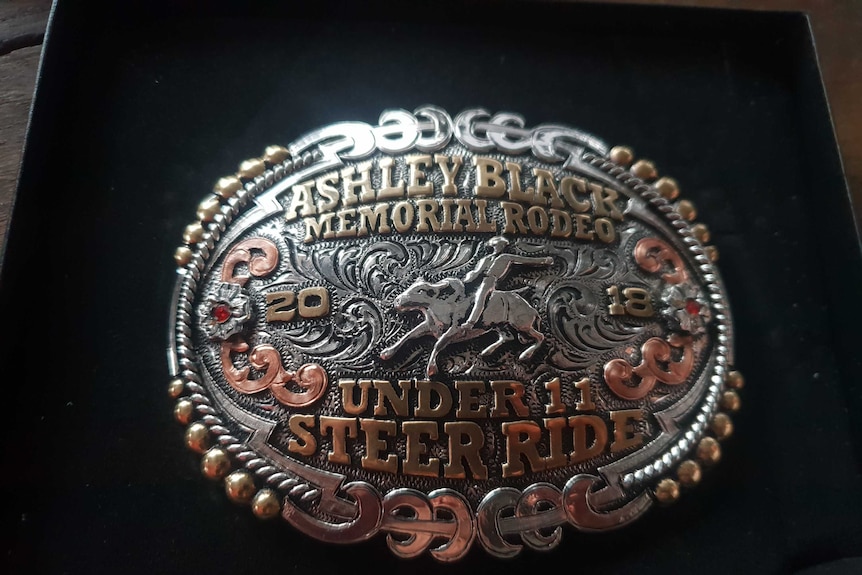 A close-up of a silver, copper and gold rodeo belt buckle.