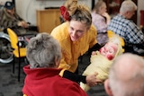A performer holds a puppet of a baby.