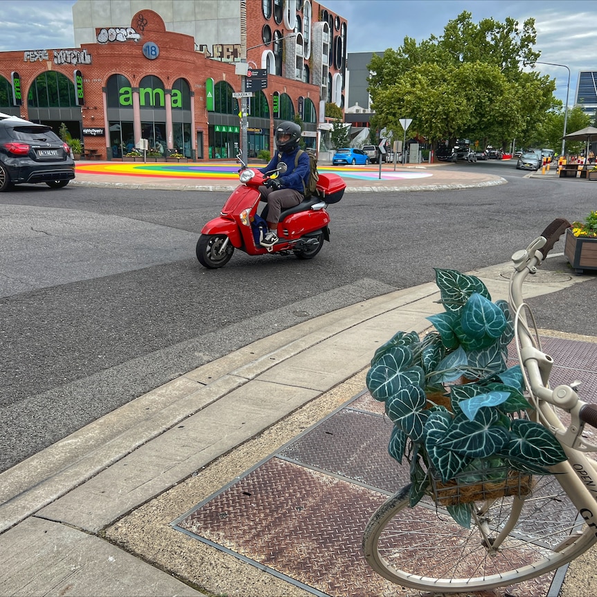 A red moped in Braddon with the rainbow roundabout in the background.
