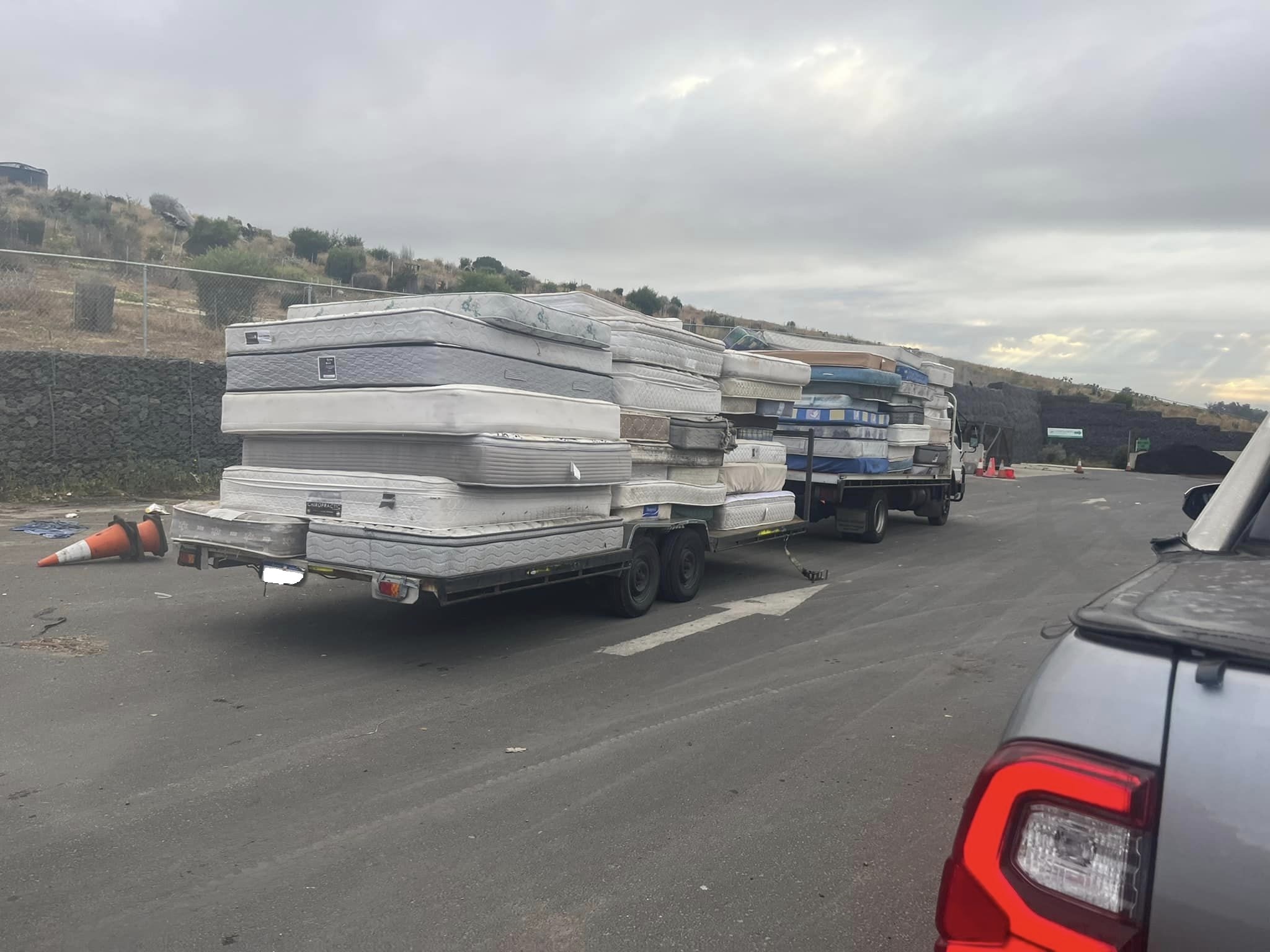 Two trailers with a stack of mattresses on the back