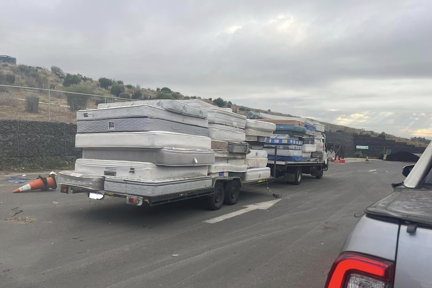Two trailers with a stack of mattresses on the back