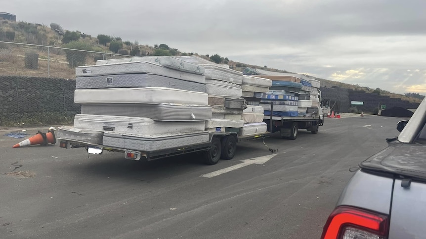 Two trailers with a stack of mattresses on the back