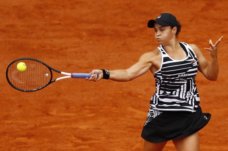 Ash Barty's bicep bulges as she returns the ball. Her face is puffed up with tension air in it.