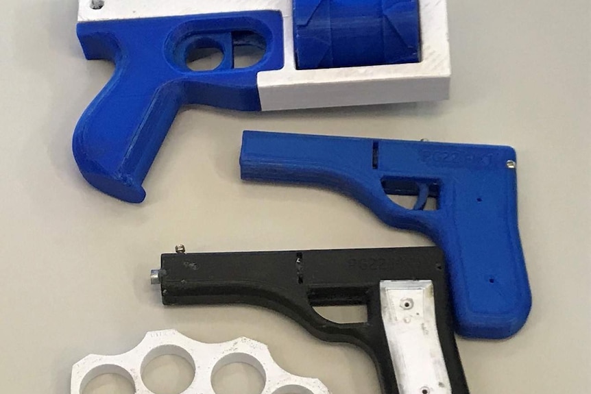 Two blue and one black and white handgun and a knuckleduster from a 3D printer found by police on the Sunshine Coast.