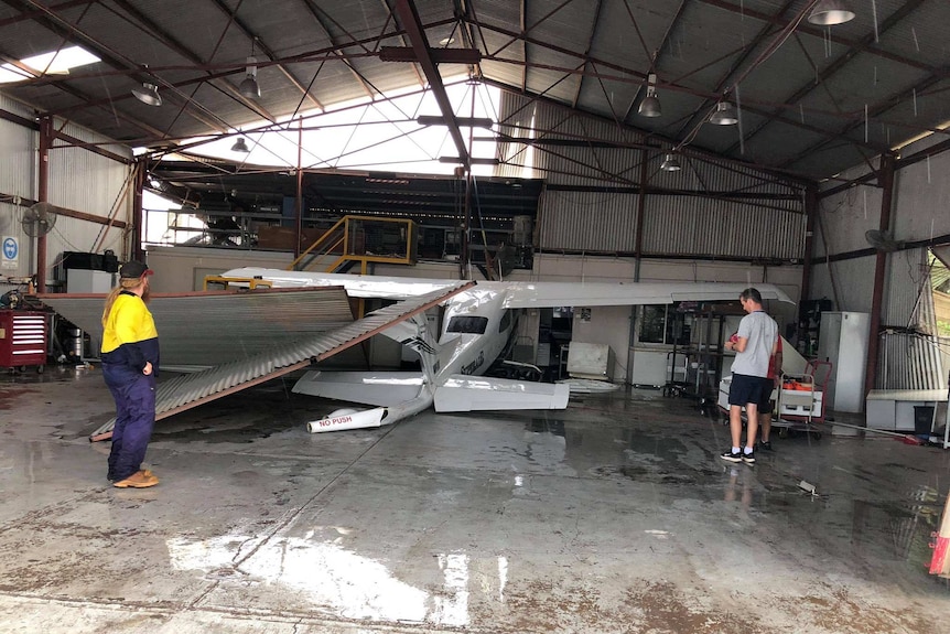 A plane pushed into wall of a damaged hangar.