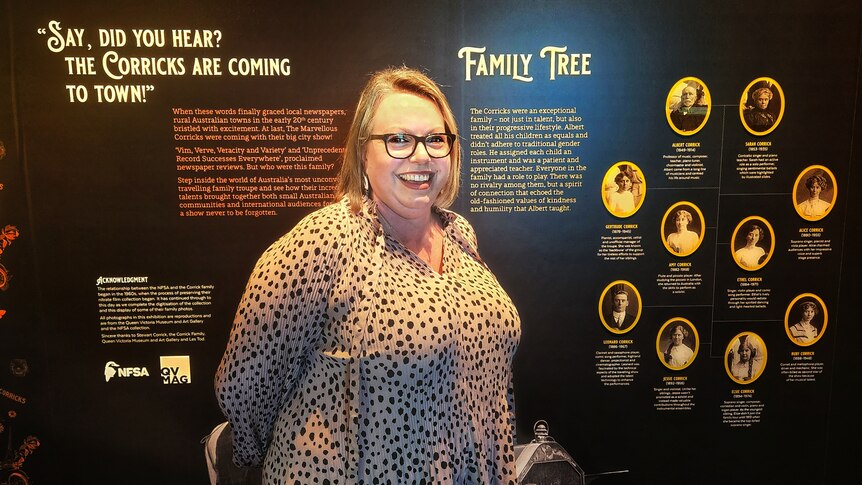 Jilliam Mackenzie is in the Corrick exhibition at the National Film and Sound Archive in front of a wall of the family tree