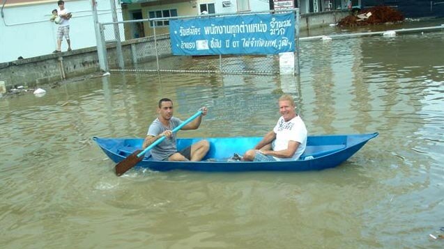 Sydney man Matthew Bennett, right, travels through floodwaters near his factory in Bangkok's north