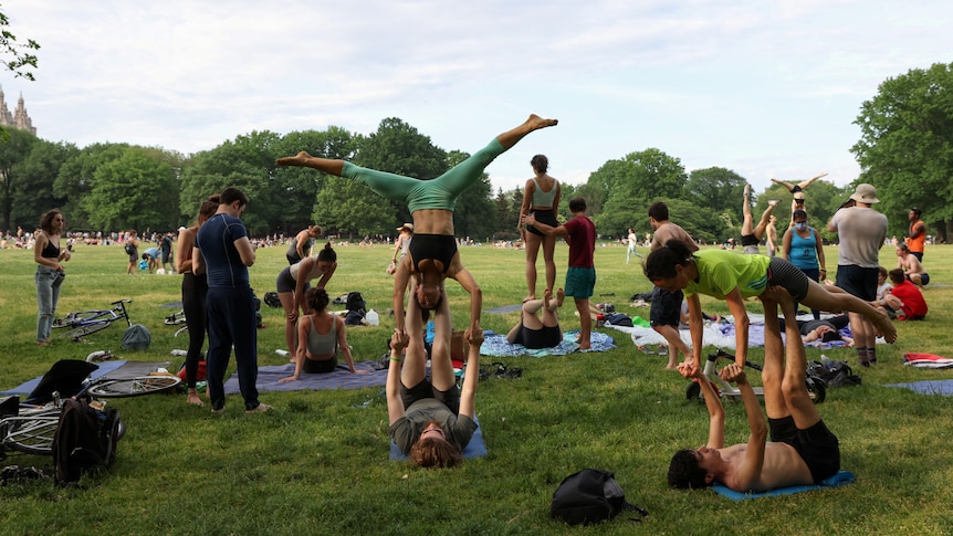 People practice gymnastics in Central Park without masks.