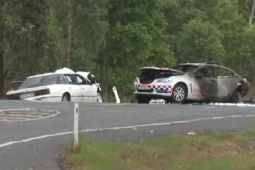 Two cars involved in a crash, one is a police car and is burnt-out from a fire