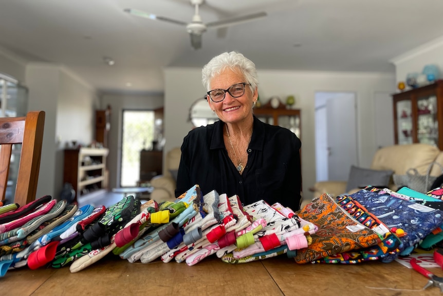 A lady sits in front of a pile of pencil cases.