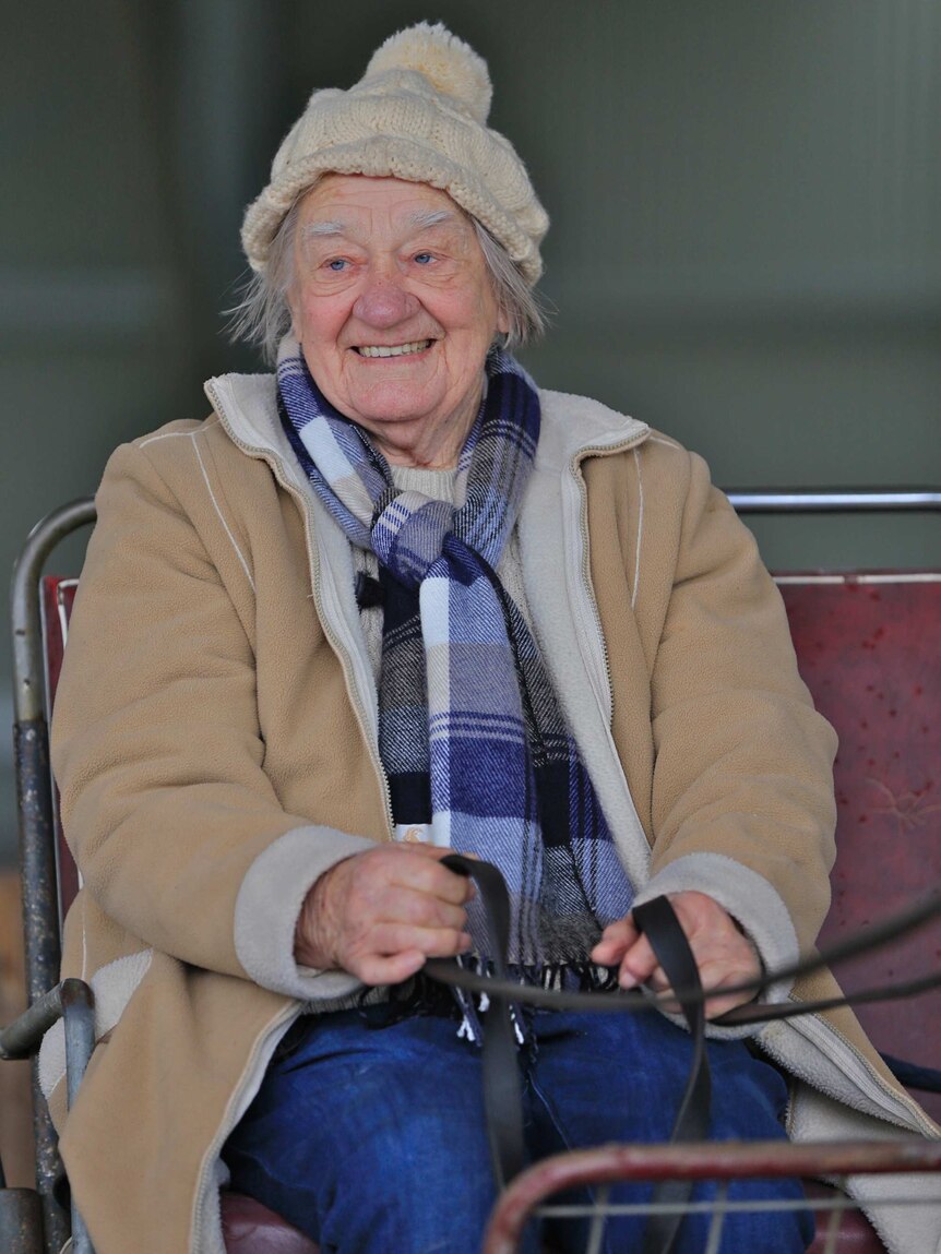 A rugged-up Margaret sits in a cart holding the reigns